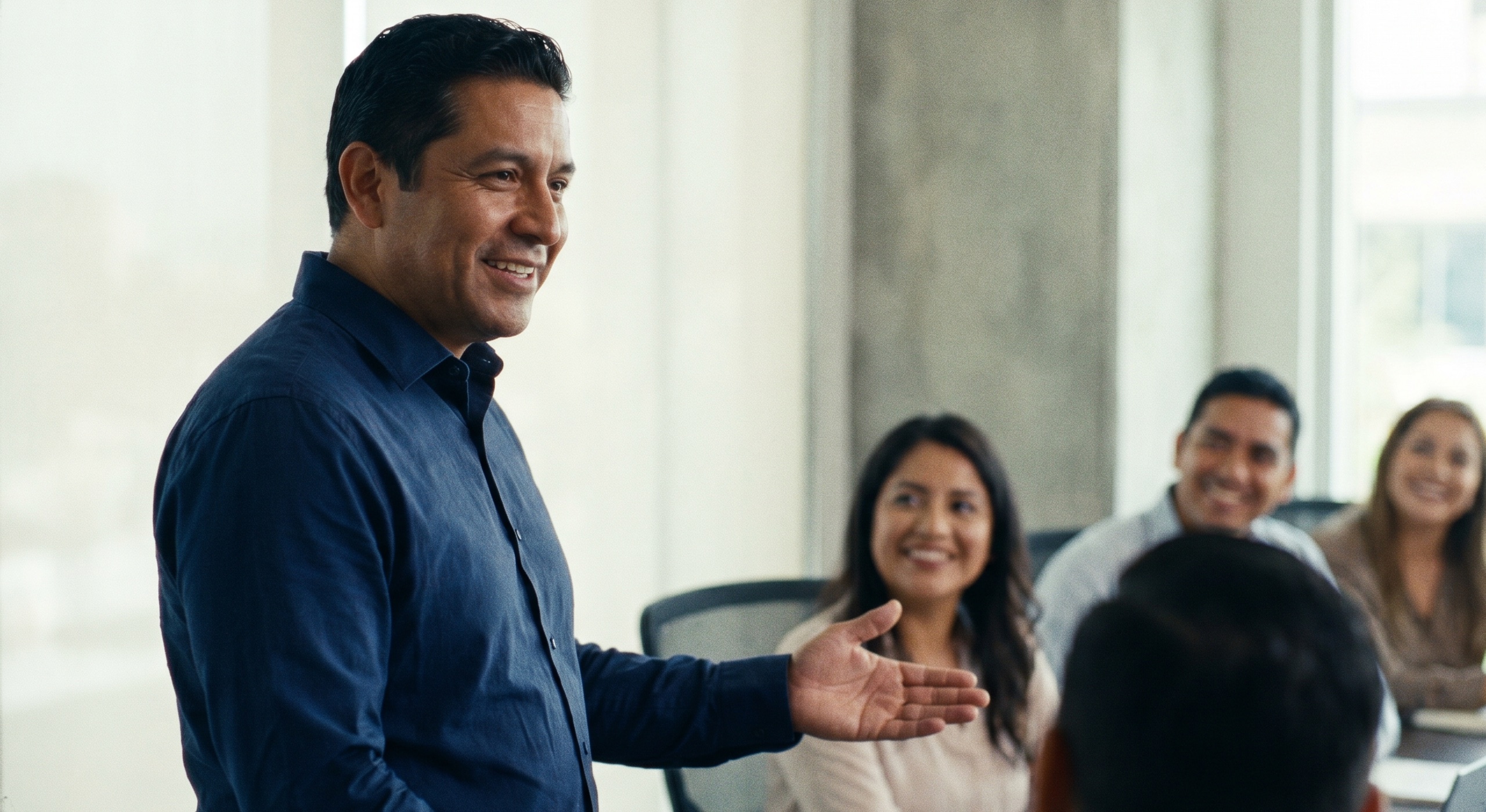 Profesional mexicano presentando ante una audiencia sonriente en una oficina moderna