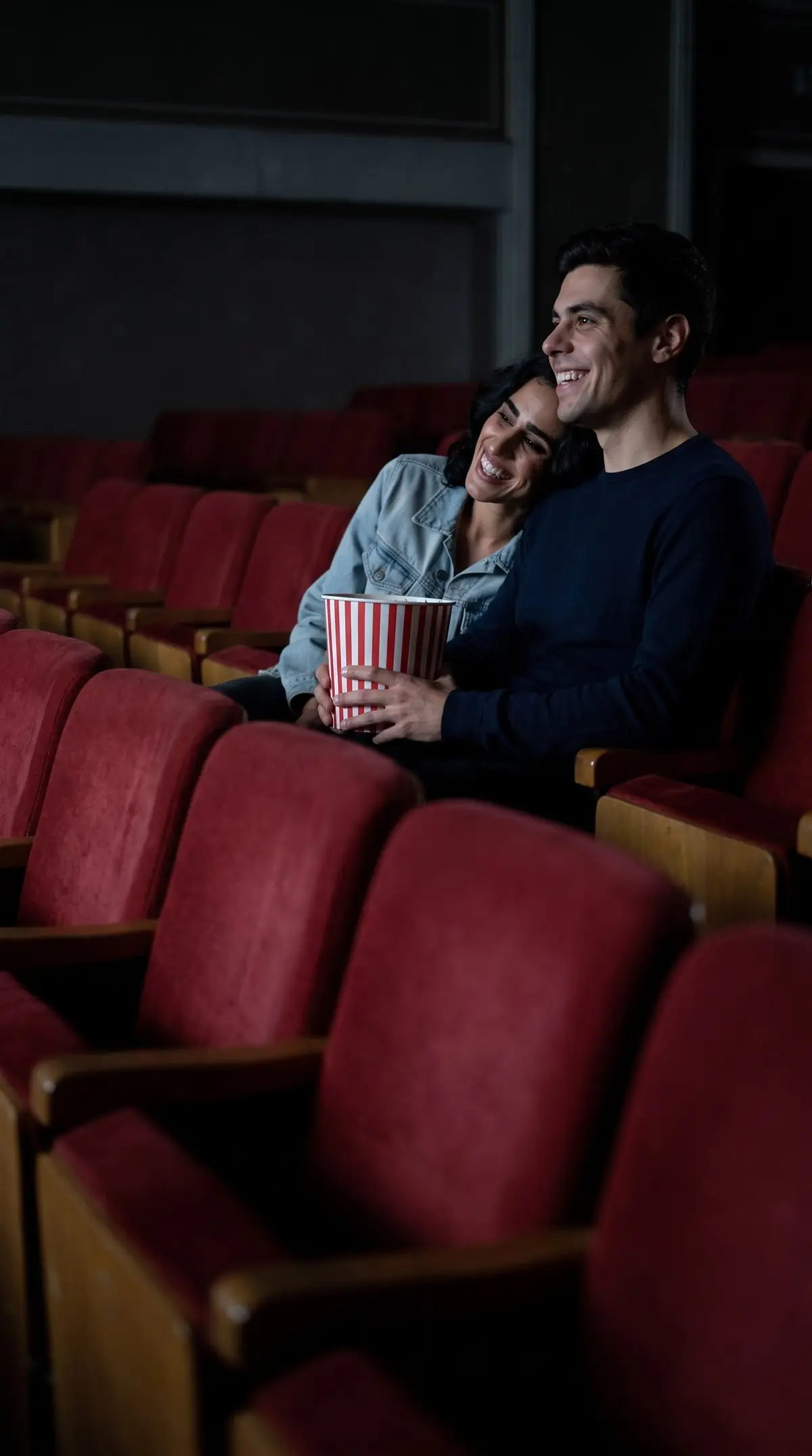 Pareja joven riendo en el cine con palomitas