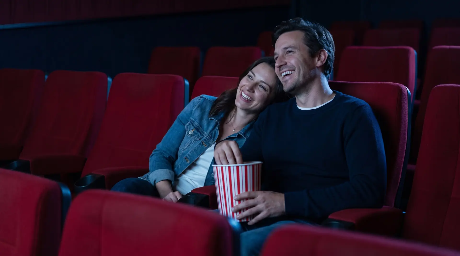 Pareja joven riendo en el cine con palomitas